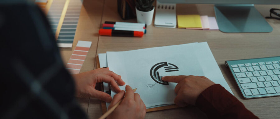 Creative team collaboration on logo design with sketch color palette and digital tools in modern office setting