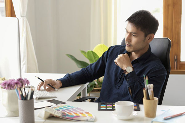 Serious male graphic designer focusing and pensive thinking creative idea on his project in office min