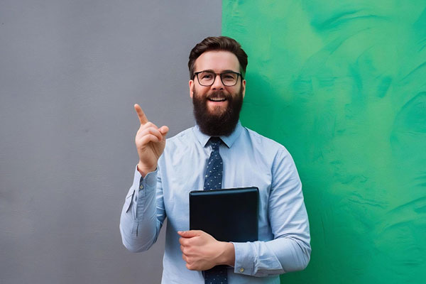 Smiling bearded man in busines clothes pointing and looking up over gray min