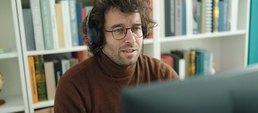 Young hispanic man student using computer and headphones studying