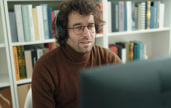 Young hispanic man student using computer and headphones studying